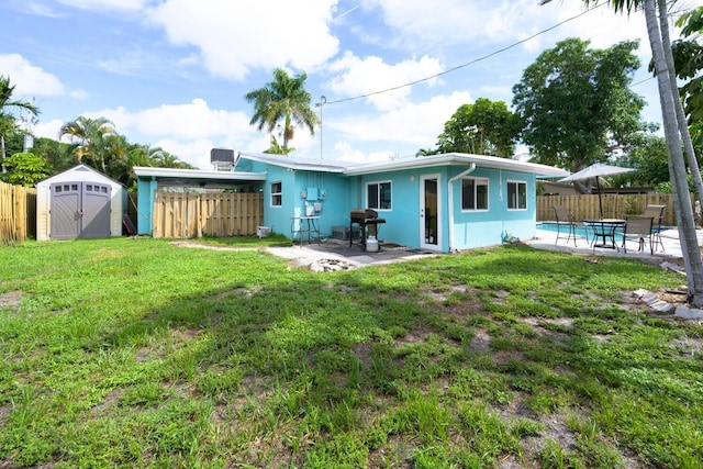 rear view of property with a storage shed, a yard, and a patio