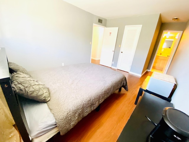 bedroom featuring hardwood / wood-style flooring and ensuite bathroom