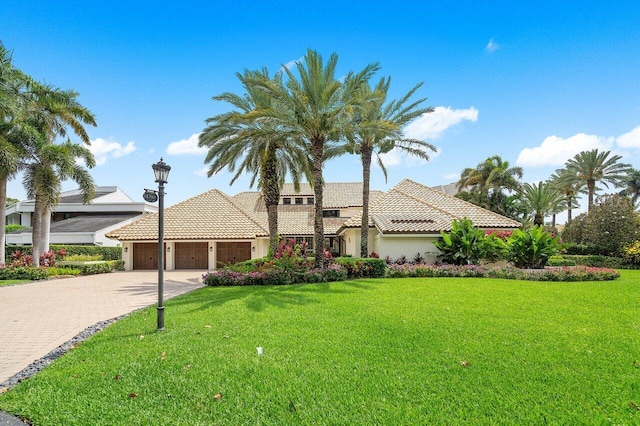 mediterranean / spanish house featuring a front yard and a garage