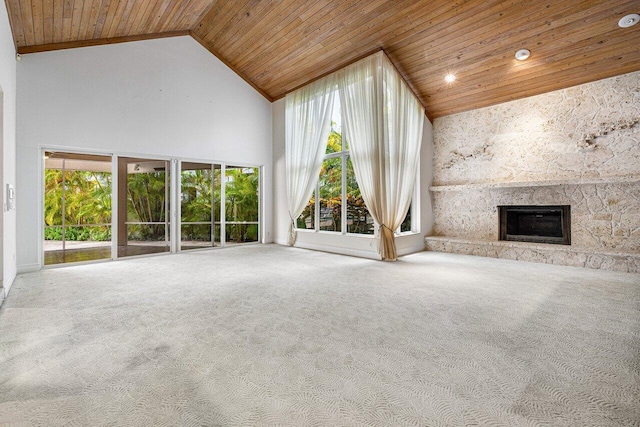 unfurnished living room with carpet floors, a stone fireplace, high vaulted ceiling, and wooden ceiling