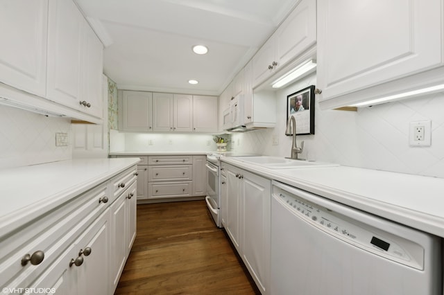 kitchen with white appliances, dark hardwood / wood-style flooring, backsplash, sink, and white cabinets