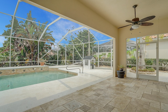 view of pool with glass enclosure, ceiling fan, a patio, and pool water feature