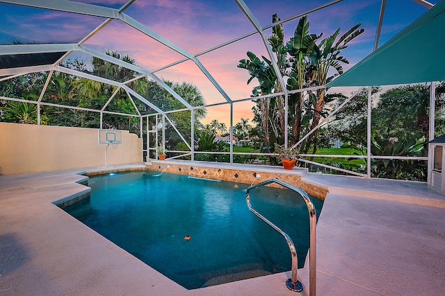 pool at dusk with a lanai and a patio area