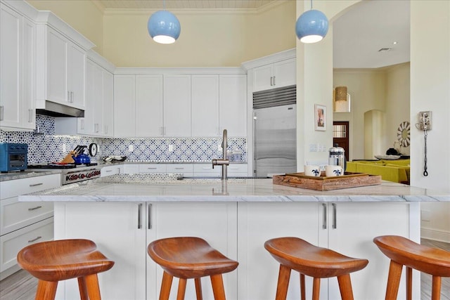 kitchen featuring white cabinets, light stone countertops, tasteful backsplash, and built in refrigerator