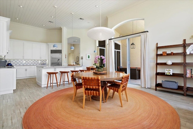 dining room with ornamental molding, light hardwood / wood-style floors, a towering ceiling, and sink