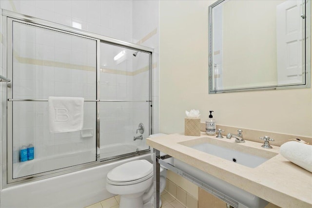 full bathroom with tile floors, sink, combined bath / shower with glass door, and toilet