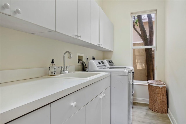 laundry area with washing machine and clothes dryer, light hardwood / wood-style flooring, hookup for a washing machine, sink, and cabinets