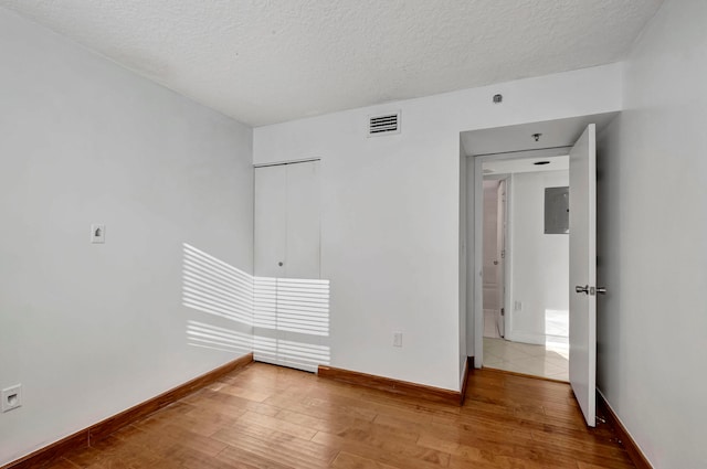 spare room with a textured ceiling and light hardwood / wood-style flooring