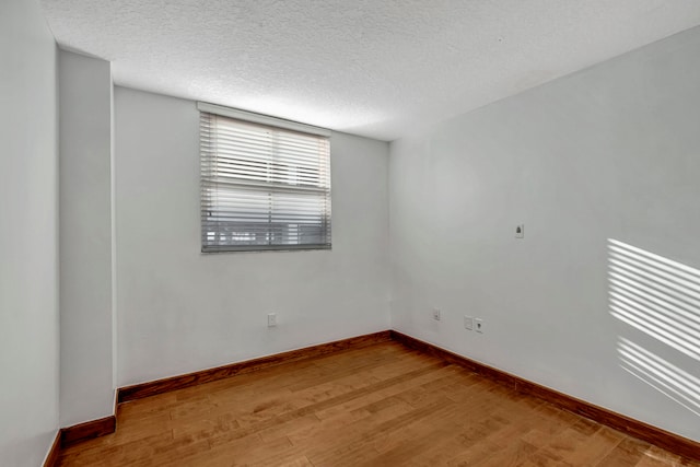 spare room with a textured ceiling and hardwood / wood-style floors