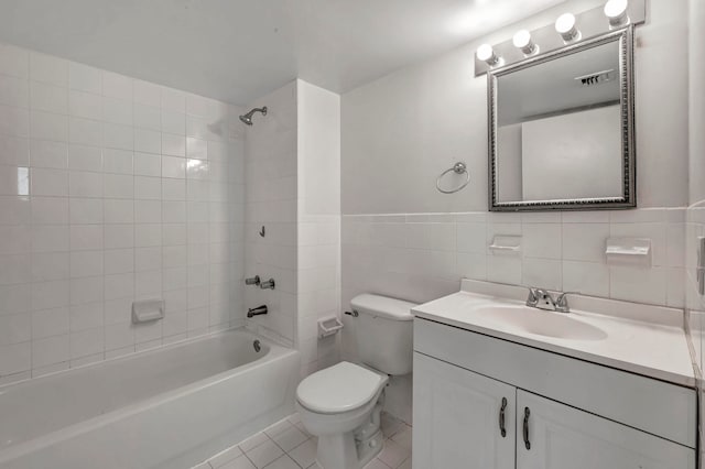 full bathroom featuring tile flooring, vanity with extensive cabinet space, tiled shower / bath combo, tile walls, and toilet