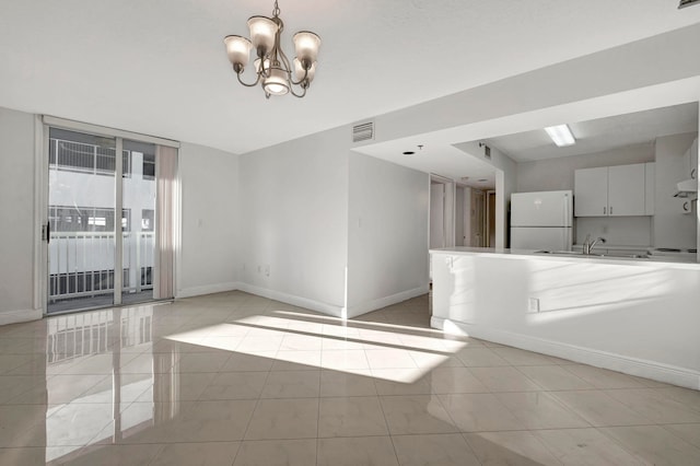 unfurnished living room featuring sink, an inviting chandelier, and light tile flooring