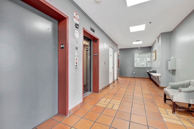 hall featuring elevator and light tile flooring