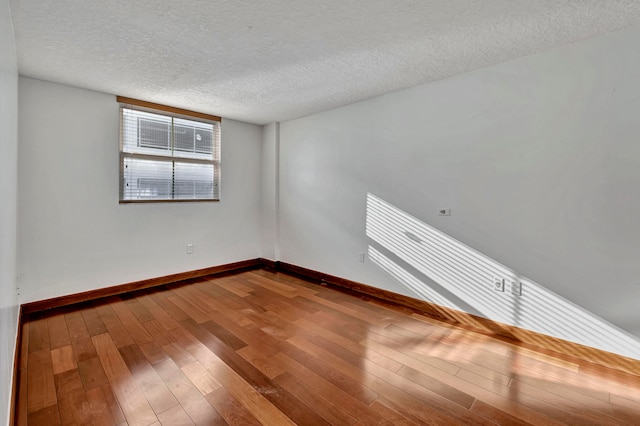 unfurnished room featuring hardwood / wood-style flooring and a textured ceiling