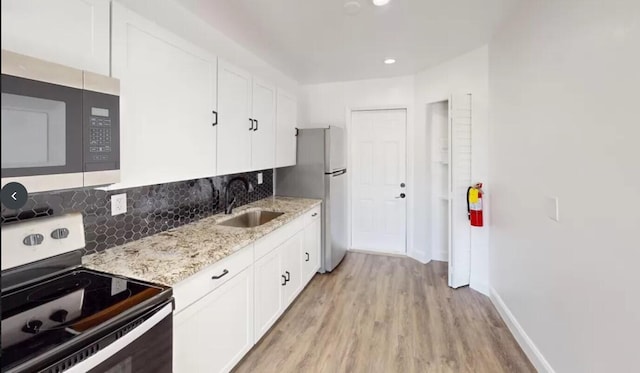 kitchen with white cabinetry, appliances with stainless steel finishes, sink, and light hardwood / wood-style flooring