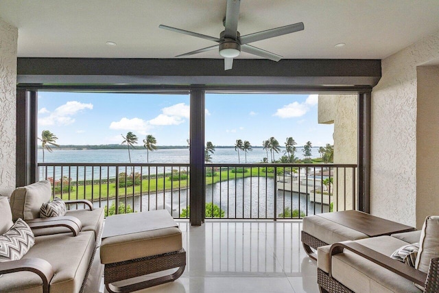 sunroom / solarium featuring ceiling fan and a water view