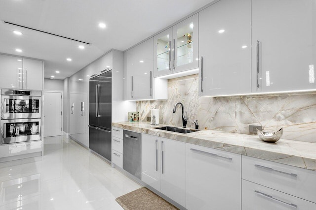 kitchen featuring light stone countertops, appliances with stainless steel finishes, sink, tasteful backsplash, and light tile floors