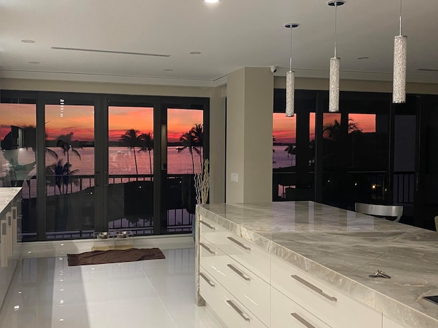 kitchen with a water view, white cabinetry, tile floors, and pendant lighting