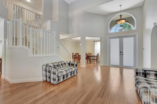 foyer with light hardwood / wood-style floors, french doors, and a high ceiling