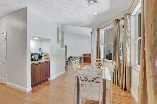 dining room featuring a textured ceiling and light hardwood / wood-style flooring