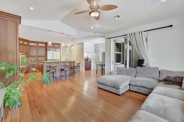 living room with ceiling fan, light wood-type flooring, and lofted ceiling