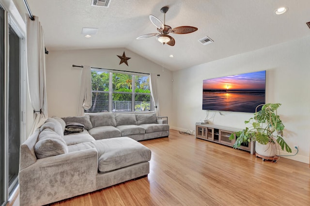 living room with a textured ceiling, ceiling fan, light wood-type flooring, and lofted ceiling