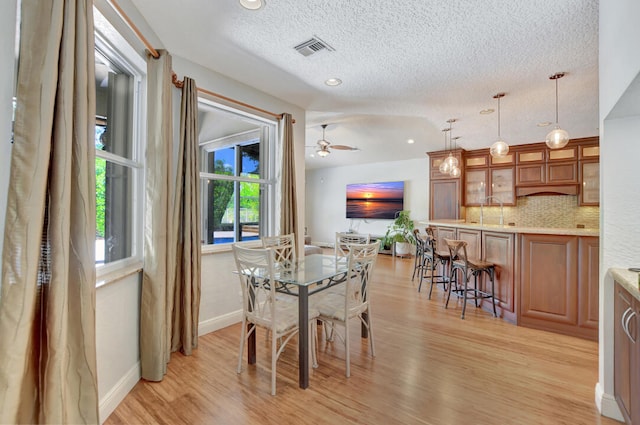 dining area featuring ceiling fan, light hardwood / wood-style floors, and a textured ceiling