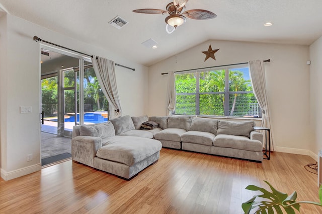 living room with ceiling fan, light hardwood / wood-style flooring, and vaulted ceiling