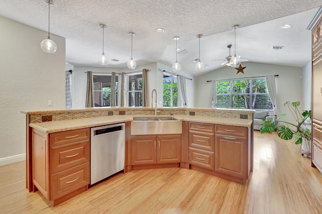 kitchen featuring vaulted ceiling, sink, stainless steel dishwasher, and light wood-type flooring