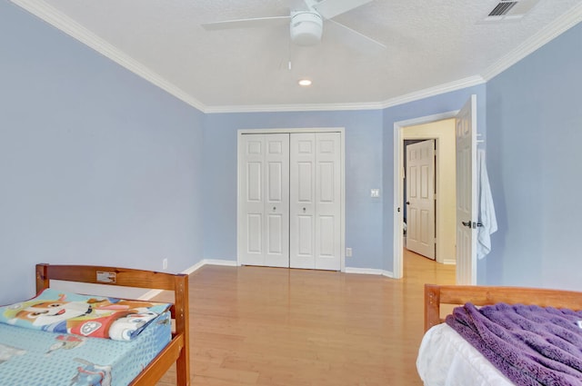 bedroom featuring a closet, ceiling fan, light hardwood / wood-style floors, and crown molding