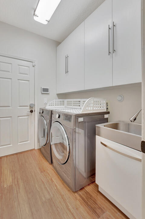 washroom featuring cabinets, sink, light hardwood / wood-style flooring, and washing machine and dryer