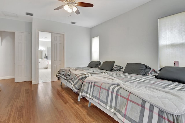 bedroom with hardwood / wood-style flooring, ceiling fan, and ensuite bath