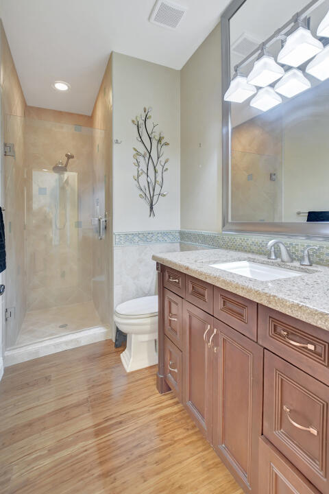 bathroom with tiled shower, vanity, toilet, and hardwood / wood-style floors