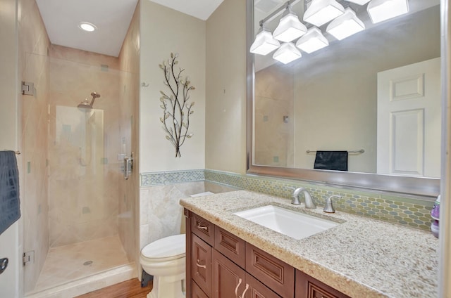 bathroom featuring tiled shower, hardwood / wood-style flooring, tasteful backsplash, vanity, and toilet