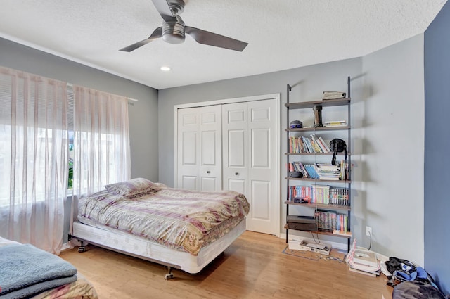 bedroom featuring light hardwood / wood-style floors, a textured ceiling, a closet, and ceiling fan