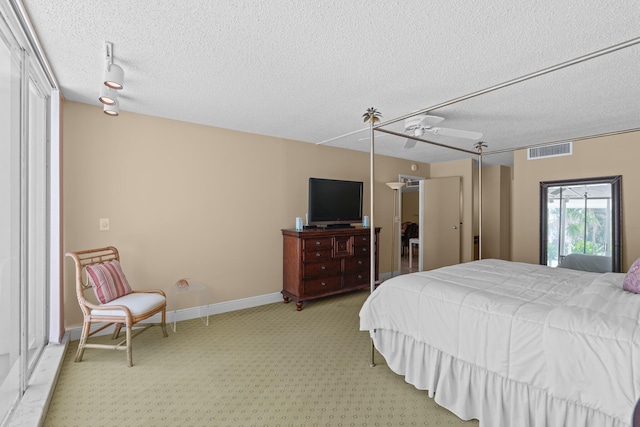 carpeted bedroom with ceiling fan, a textured ceiling, and track lighting