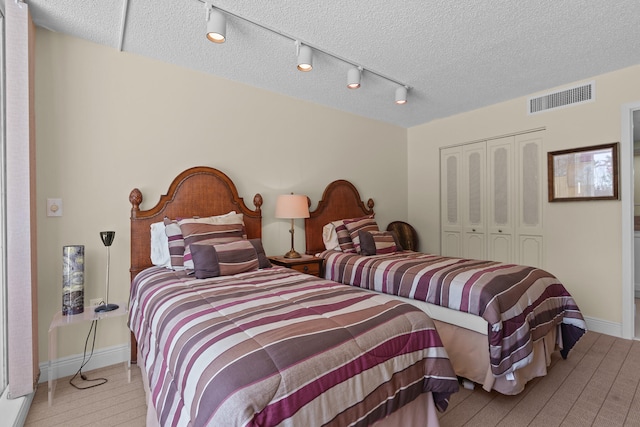 bedroom featuring a closet, a textured ceiling, and rail lighting