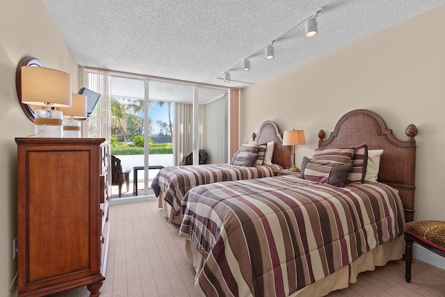 bedroom featuring access to exterior, a textured ceiling, track lighting, and a wall of windows