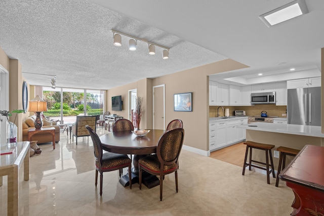 tiled dining area featuring floor to ceiling windows, sink, a textured ceiling, and track lighting