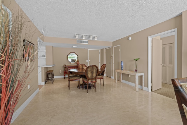 tiled dining area with a textured ceiling and track lighting