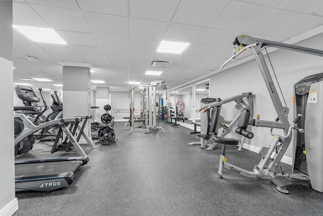 gym with water heater and a paneled ceiling