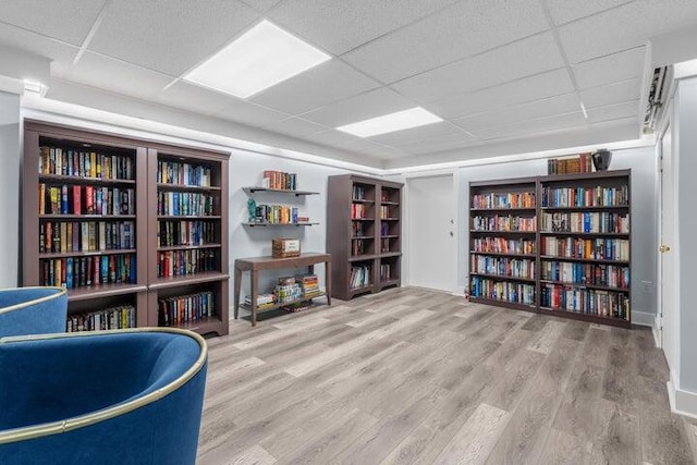 living area with light hardwood / wood-style floors and a paneled ceiling