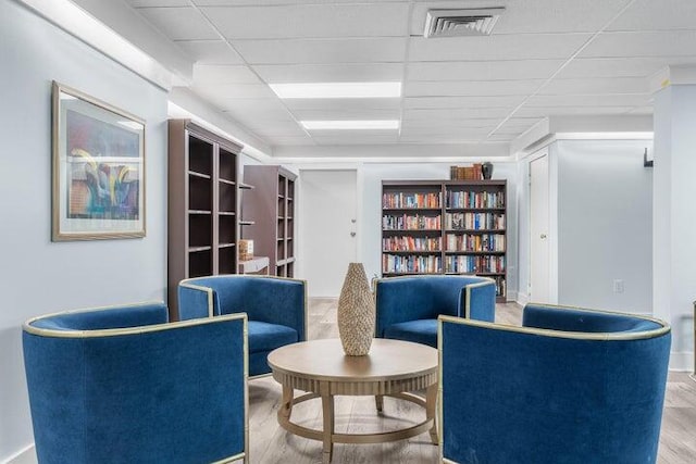 sitting room with hardwood / wood-style floors and a drop ceiling