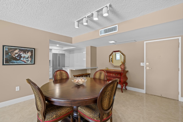 tiled dining area featuring a textured ceiling and rail lighting