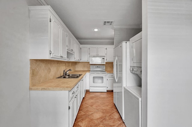 kitchen with sink, tasteful backsplash, stacked washer and dryer, white appliances, and white cabinets