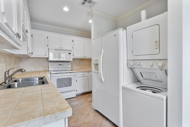 kitchen featuring white cabinetry, sink, ornamental molding, stacked washer / drying machine, and white appliances