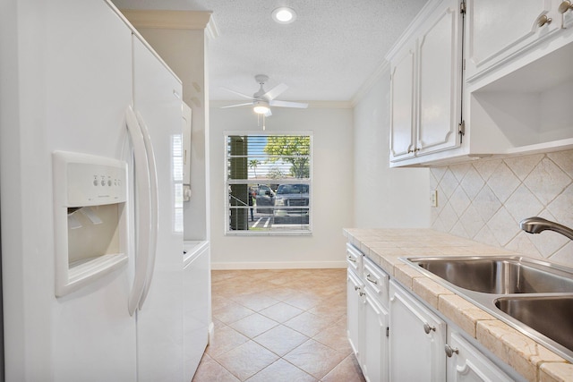 kitchen featuring white cabinetry, sink, a textured ceiling, and white fridge with ice dispenser