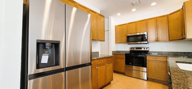 kitchen with appliances with stainless steel finishes and dark stone counters