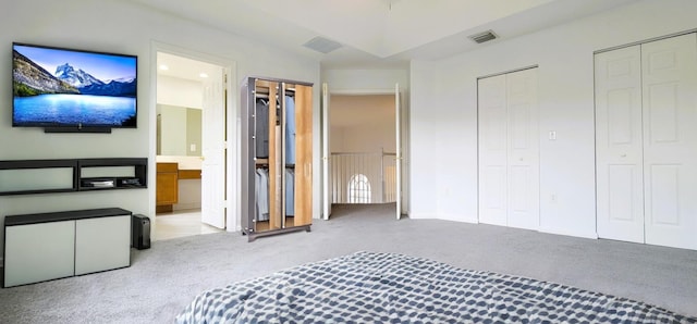 unfurnished bedroom featuring two closets, connected bathroom, and light colored carpet