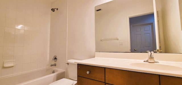 full bathroom with tiled shower / bath, vanity, and toilet