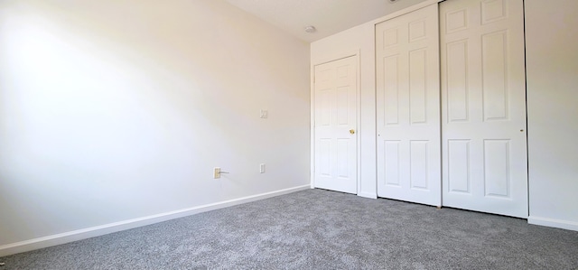 unfurnished bedroom featuring dark carpet and a closet